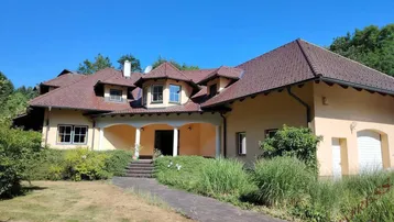 Großzügiges Einfamilienhaus mit weitläufigem Vorgarten und einladendem Eingangsbereich unter einem Vordach.
