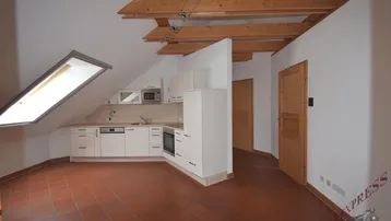 Offene Küche im Dachgeschoss mit Einbauschränken, Dachfenster und Terrakottafliesen.