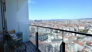 Moderner Balkon mit Holzboden und Glasgeländer bietet einen weiten Blick über die Stadt.