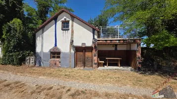 Rustikales Gebäude mit überdachtem Sitzbereich und einer kleinen Terrasse im Obergeschoss.