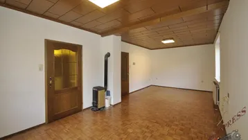 Helles Wohnzimmer mit Parkettboden, Holzdecke und einem gemütlichen Holzofen.