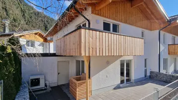 Moderne Neubau-Doppelhaushälfte mit Holzverkleidung, Balkon, Terrasse und effizienter Wärmepumpe.