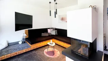 Gemütliches Wohnzimmer mit integrierter Sitzbank, modernem Kamin und dunklem Fliesenboden.