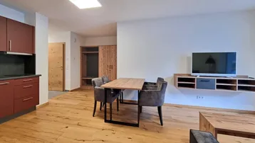 Offener Wohn- und Essbereich mit integrierter Küche, Holzboden und moderner Einrichtung.