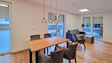 Heller Wohn- und Essbereich mit Holzboden, modernen Möbeln und Zugang zur Terrasse.