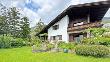 Charmantes Einfamilienhaus mit gepflegtem Garten und Blick auf die umliegende Berglandschaft.