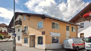 Gebäudeansicht mit hellgelber Fassade und Balkonen an einem sonnigen Tag.