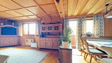 Traditioneller Wohn- und Essbereich mit viel Holzvertäfelung, rustikalen Möbeln und Teppichboden.