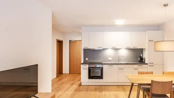 Moderne Einbauküche mit weißen Schränken, integrierten Geräten und Holzboden.