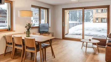 Heller Wohn- und Essbereich mit Holzboden, modernem Esstisch und Zugang zu einer verschneiten Terrasse.