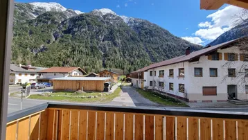Geräumiger Balkon mit Holzboden und atemberaubendem Bergblick auf die umliegende Alpenlandschaft.