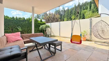 Großzügige, möblierte Terrasse mit Steinboden und Blick ins Grüne, perfekt zum Entspannen.