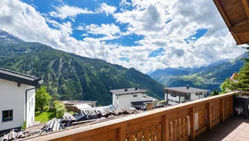 Geräumiger Balkon mit traditionellem Holzgeländer und weitem Blick auf die umliegende Berglandschaft.