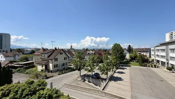 Weitläufiger Blick über die Nachbarschaft mit Bäumen und Bergen im Hintergrund.