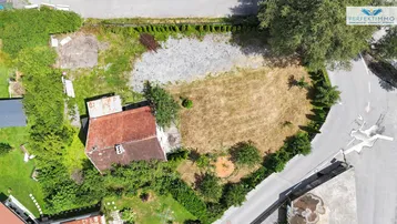 Luftaufnahme eines Grundstücks mit einem Haus, Rasenflächen und umliegender Vegetation.