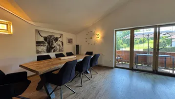Geräumiger Essbereich mit Holztisch, modernen Stühlen und direktem Zugang zum Balkon.