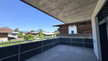Geräumiger Balkon mit Fliesenboden, moderner Brüstung und weitem Blick auf die umliegende Berglandschaft.