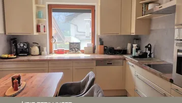 Helle Küche mit beigefarbenen Schränken, Granitarbeitsplatte und Blick ins Grüne.