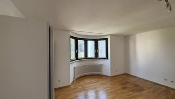 Helles Zimmer mit Erkerfenster und Parkettboden, ideal als Wohn- oder Schlafzimmer.
