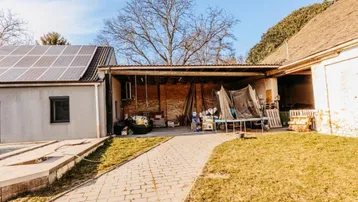 Rückansicht des Hauses mit Photovoltaikanlage auf dem Dach und einem offenen Unterstand.