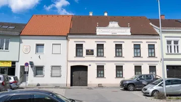Historisches Gebäude mit klassischer Fassade und Satteldach an einer Straße.