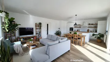Heller, offener Wohn-Essbereich mit integrierter Küche, modernem Design und Holzboden.