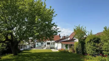 Großer, gepflegter Garten mit Rasenfläche, altem Baumbestand und Terrasse hinter dem Haus.
