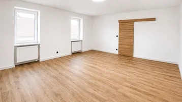 Heller, leerer Raum mit Laminatboden, weißen Wänden und moderner Schiebetür.