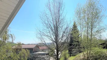 Weitläufiger Blick über die grüne Landschaft und Dächer von einem erhöhten Standpunkt.