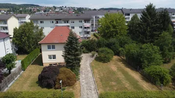 Luftaufnahme eines Einfamilienhauses mit großem Garten und Blick auf die umliegende Wohngegend.