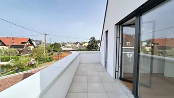 Langer Balkon mit Fliesenboden und Blick auf die umliegende Wohngegend und Grünflächen.