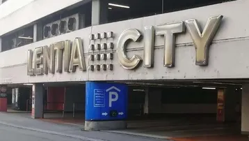 Eingang zu einem mehrstöckigen Parkhaus mit Beschilderung und Zufahrt in urbaner Umgebung.