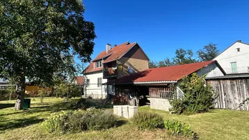 Gepflegter Gartenbereich mit Rasenfläche, Bäumen und Blick auf das Wohnhaus.