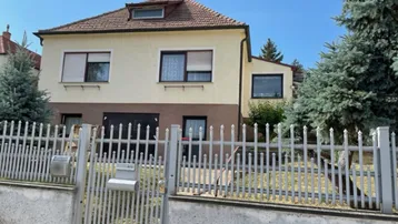 Vorderansicht des Hauses mit einem gepflegten Vorgarten und einem stabilen Metallzaun.