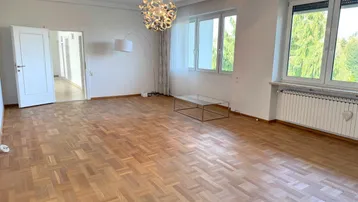 Helles Wohnzimmer mit Parkettboden, großen Fenstern und Blick ins Grüne.