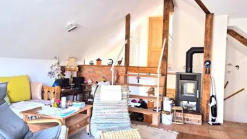 Wohnzimmer im Dachgeschoss mit Kaminofen, Holzbalken und rustikalem Charme.