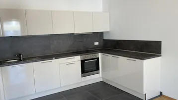 Moderne Küche mit weißen Hochglanzfronten, dunkler Arbeitsplatte und integrierten Geräten.