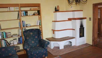 Gemütliches Wohnzimmer mit Kachelofen, Holzboden und einem Bücherregal.