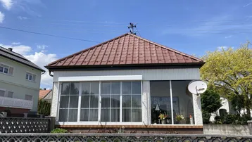 Vorderansicht des Hauses mit großen Fenstern und Satteldach.