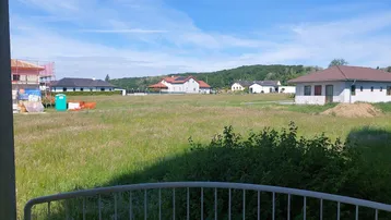 Weitläufiger Blick von einem Balkon über grüne Felder und ländliche Bebauung.