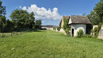 Weitläufiger Gartenbereich mit grüner Wiese, umzäuntem Grundstück und einem kleinen Nebengebäude.