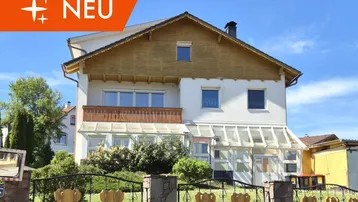 Traditionelles Einfamilienhaus mit weißer Fassade, Holzverkleidung und einem Wintergarten im Erdgeschoss.