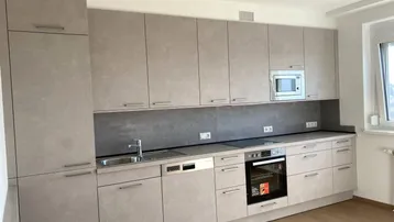 Moderne Einbauküche in Grau mit integrierten Geräten und Holzfußboden.