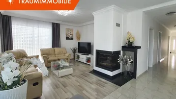 Geräumiges Wohnzimmer mit modernem Kamin, hellem Boden und bequemen Sofas für entspannte Abende.