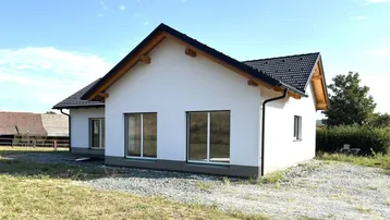 Modernes Einfamilienhaus im Neubau mit weißer Fassade und großen Fenstern in ländlicher Umgebung.
