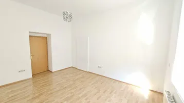 Helles, leeres Zimmer mit Parkettboden und einer Tür, bereit zur individuellen Gestaltung.