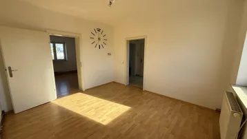Helles Zimmer mit Parkettboden und viel Tageslicht, ideal als Wohn- oder Schlafzimmer nutzbar.