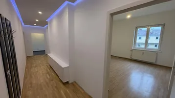 Moderner Flur mit indirekter Beleuchtung, Einbauschrank und Zugang zu weiteren Räumen.