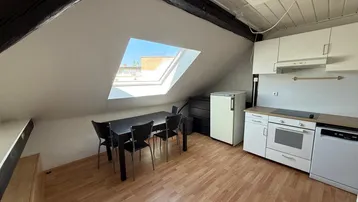 Helle Dachgeschossküche mit Essbereich, Einbauküche und großem Dachfenster.