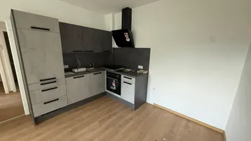 Moderne Einbauküche in Grau und Schwarz mit Laminatboden, bereit für den Erstbezug.
